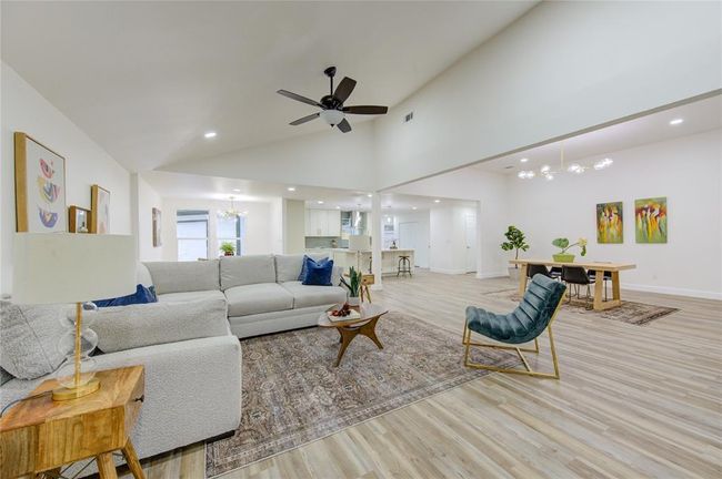 The luxury vinyl floors extend throughout the room, enhancing the modern aesthetic, while the open-concept layout allows for easy flow into the dining area and kitchen. This living room is ideal for relaxation, entertaining, or enjoying cozy nights by the fire. | Image 6