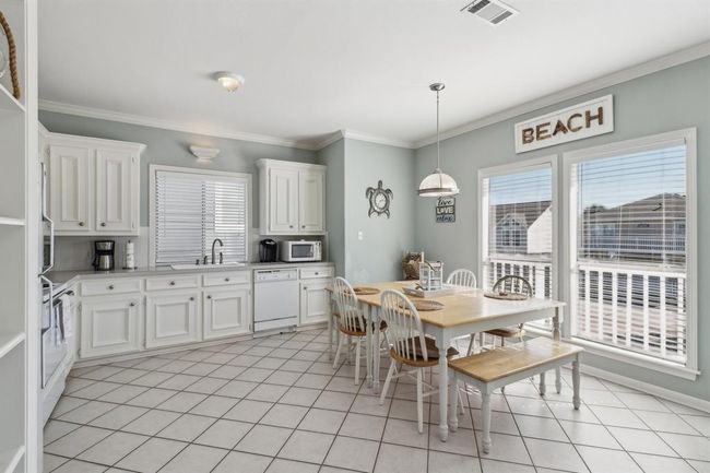 This eat-in kitchen is a perfect blend of functionality and charm, offering ample cabinet storage to keep everything neatly organized. The generous counter space makes meal preparation a breeze. Large windows in the dining area provide stunning views of the beach, allowing you to enjoy the coastal scenery while sipping your morning coffee or hosting a meal. The bright, airy atmosphere and practical layout make this space a standout feature of the home. | Image 7