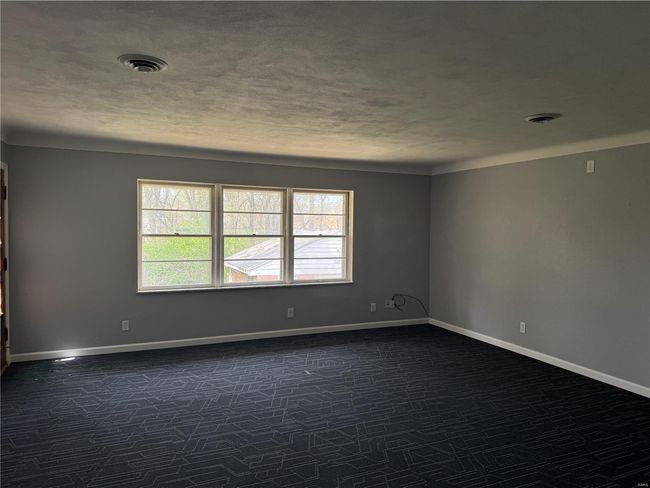 Spare room featuring dark colored carpet, a textured ceiling, baseboards, and visible vents | Image 11