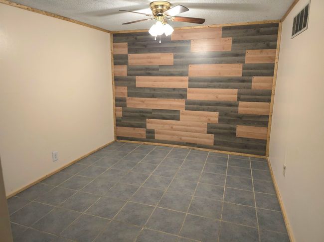 Empty room featuring ceiling fan, a textured ceiling, and wood walls | Image 18