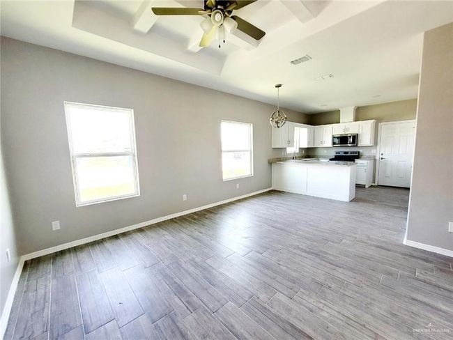 Kitchen with appliances with stainless steel finishes, open floor plan, a peninsula, white cabinets, and ceiling fan | Image 8