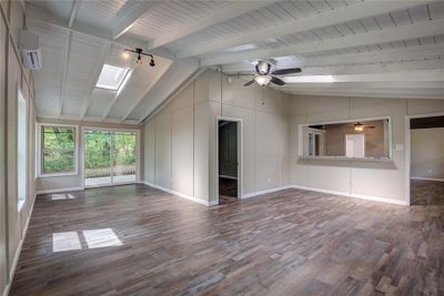 Unfurnished living room with ceiling fan, lofted ceiling with skylight, and hardwood / wood-style flooring | Image 2