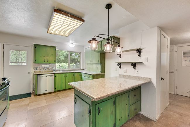 Kitchen featuring appliances with stainless steel finishes, green cabinets, a peninsula, and a sink | Image 12