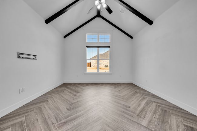 Unfurnished room featuring vaulted ceiling with beams, visible vents, ceiling fan, and baseboards | Image 12