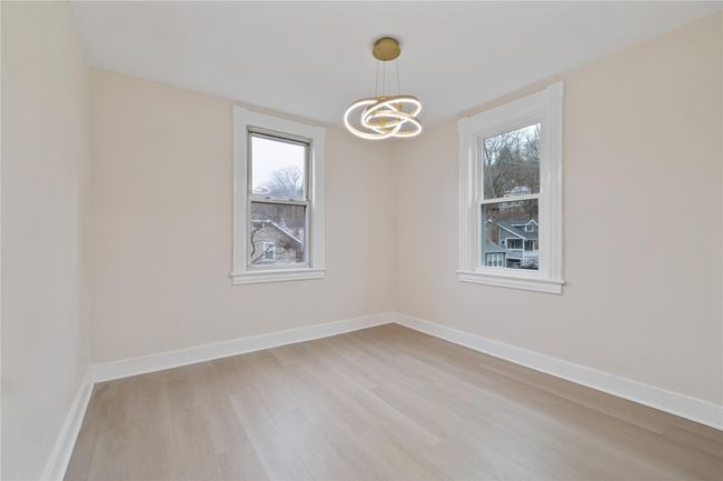 Spare room with light wood-style flooring, baseboards, plenty of natural light, and an inviting chandelier | Image 13