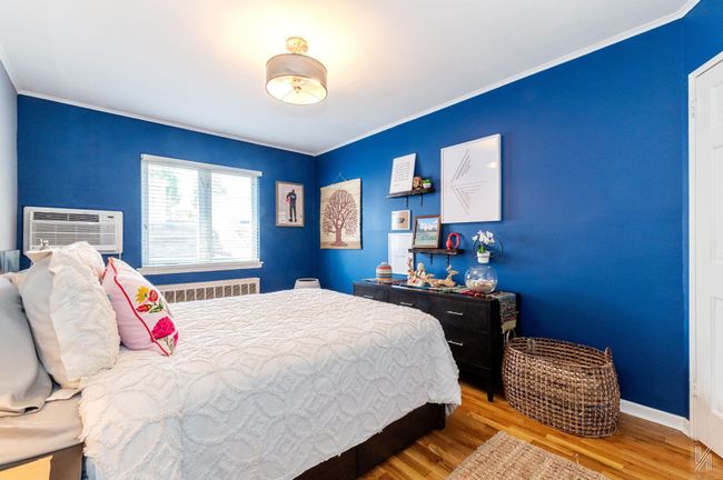 Bedroom featuring wood finished floors, crown molding, baseboards, and a wall unit AC | Image 8