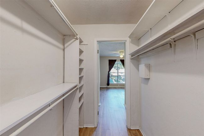 A bright walk-in closet with built-in shelves designed for storage and easy access. | Image 24