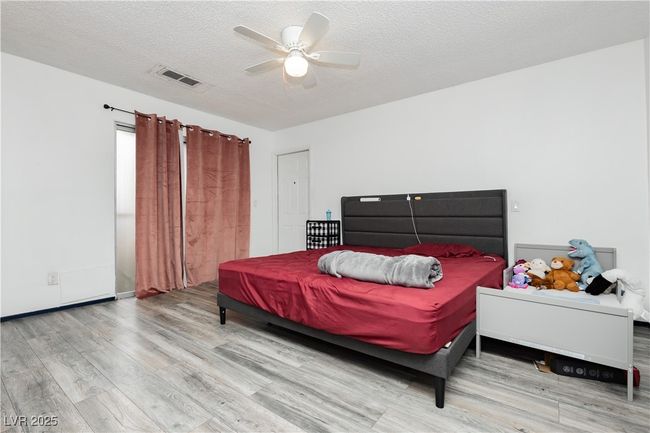 Bedroom featuring wood finished floors, a textured ceiling, and a ceiling fan | Image 11