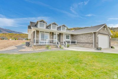 New england style home with a mountain view, a front lawn, covered porch, and a garage | Image 2