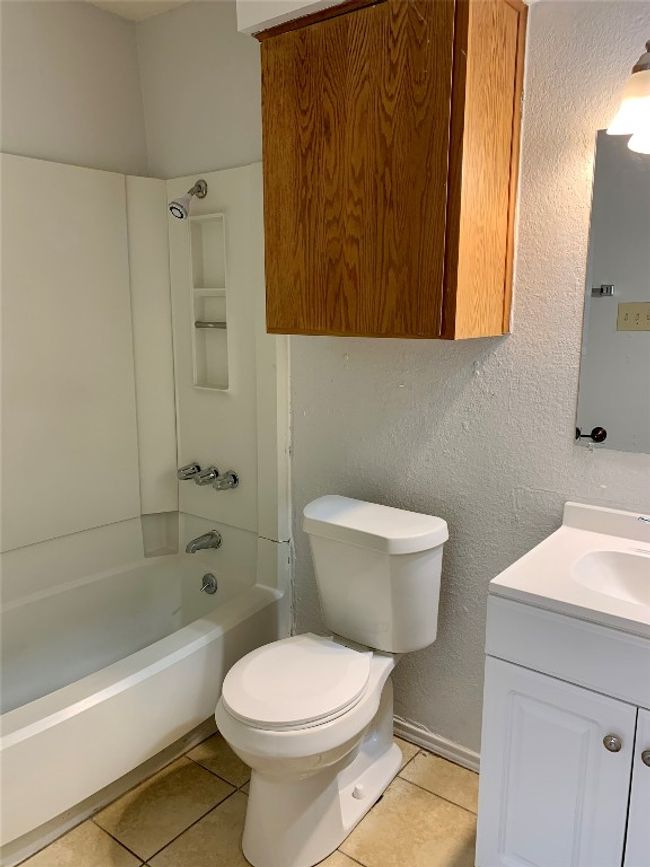 Full bath with tile patterned floors, toilet, vanity, washtub / shower combination, and a textured wall | Image 11