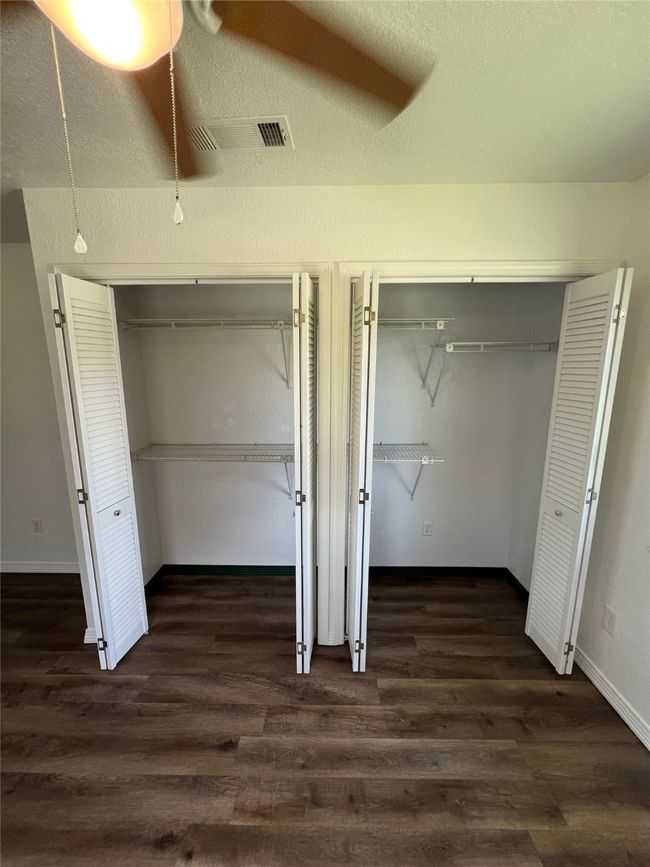 Unfurnished bedroom with dark wood-type flooring, two closets, and ceiling fan | Image 7