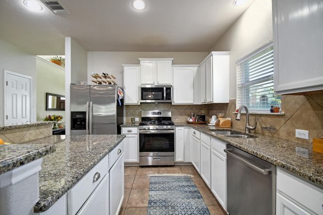 Stainless steel appliances, abundant cabinet/counter space, and a graceful tile backsplash throughout. | Image 12