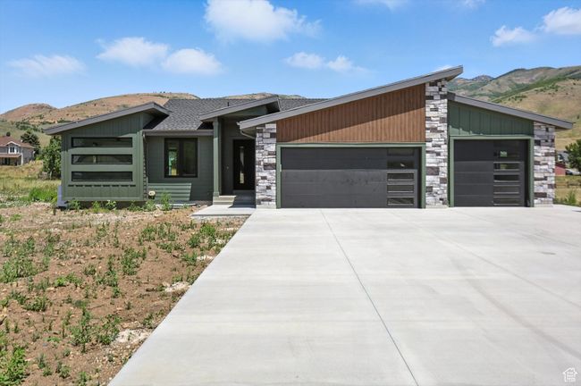 Mid-century modern home with a garage, a mountain view, stone siding, and driveway | Image 60