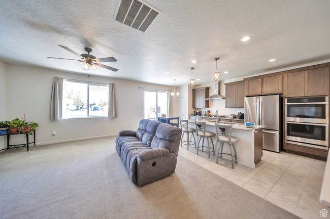 Living area with light tile patterned flooring, visible vents, recessed lighting, light colored carpet, and ceiling fan | Image 8