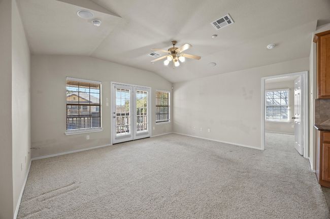Unfurnished room featuring lofted ceiling, ceiling fan, light colored carpet, visible vents, and baseboards | Image 6