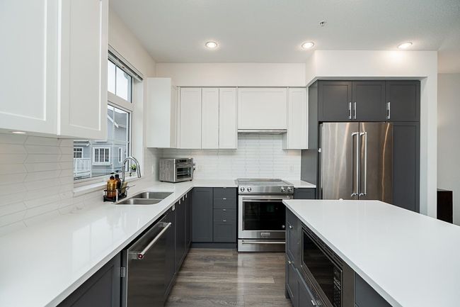 Kitchen featuring dark wood finished floors, stainless steel appliances, light countertops, backsplash, and a sink | Image 12