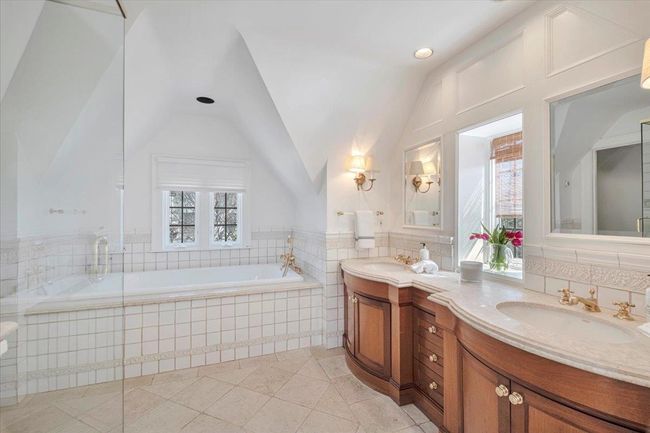 Primary bathroom with tile patterned floor, custom vanities, high end European hardware and plenty of natural light, two sinks, lofted ceiling, shower and tub. | Image 14