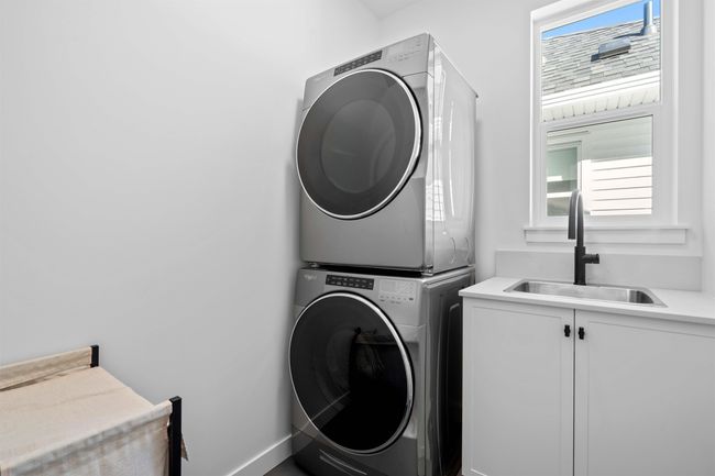 Laundry room featuring baseboards, cabinet space, stacked washer and clothes dryer, and a sink | Image 28