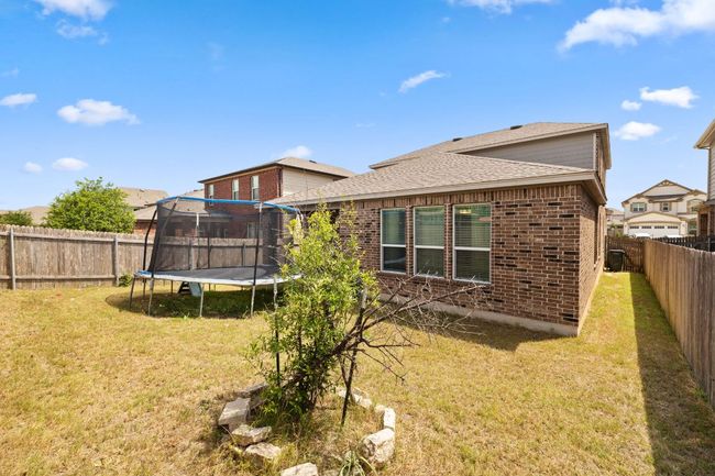 Rear view of house featuring a trampoline, brick siding, a fenced backyard, and roof with shingles | Image 33