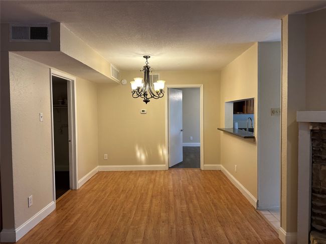 Unfurnished dining area featuring wood finished floors, a chandelier, a fireplace, and a textured ceiling | Image 9