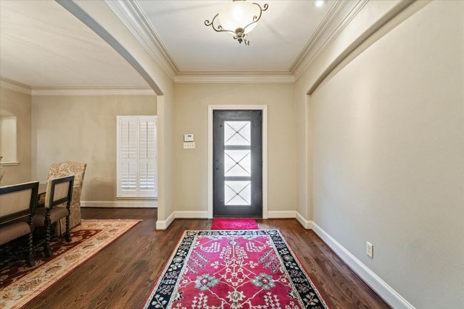 Entryway with arched walkways, dark wood-type flooring, crown molding, and baseboards | Image 6