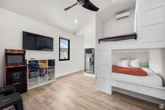 Bedroom with an AC wall unit, light hardwood / wood-style flooring, ceiling fan, and vaulted ceiling | Image 36