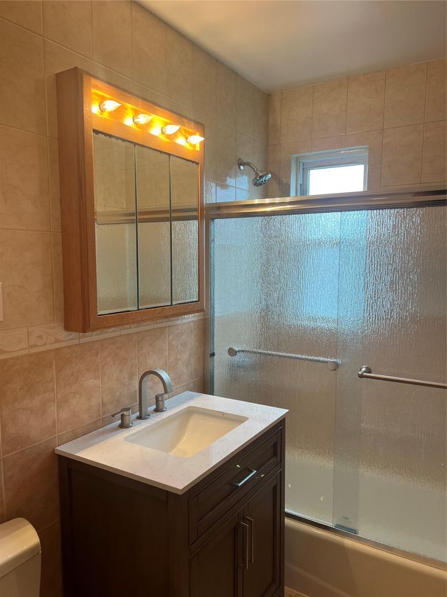 Full bathroom with vanity, tile walls, and combined bath / shower with glass door | Image 5