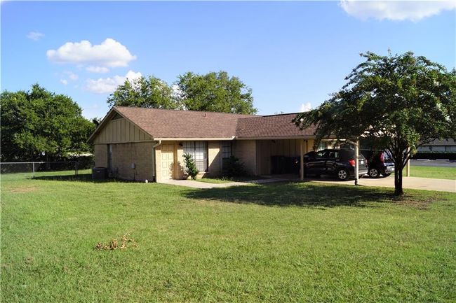 View of side of property featuring concrete driveway, brick siding, an attached carport, and board and batten siding | Image 17