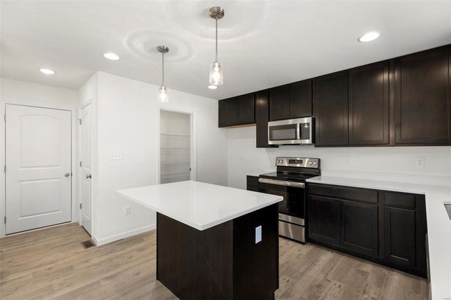 Kitchen with appliances with stainless steel finishes, hanging light fixtures, light hardwood / wood-style floors, and a center island | Image 14
