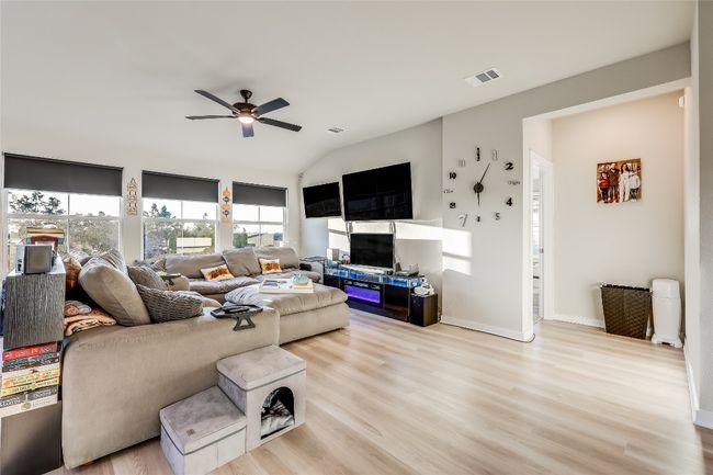 Living room featuring a ceiling fan, plenty of natural light, light wood-style flooring, vaulted ceiling, and baseboards | Image 11