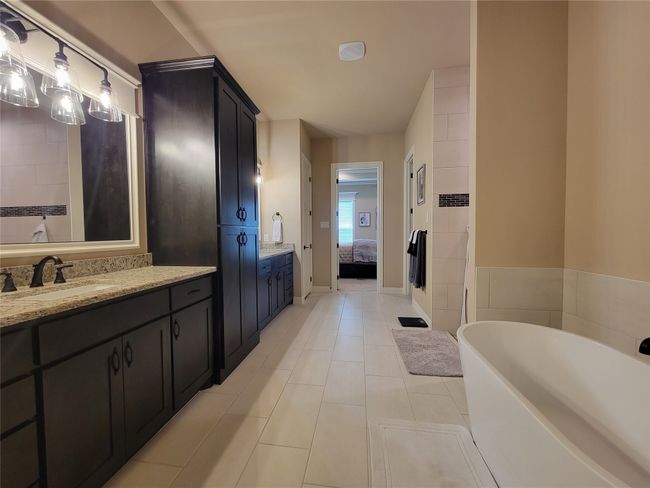 Bathroom with ensuite bathroom, a soaking tub, vanity, and tile patterned floors | Image 19