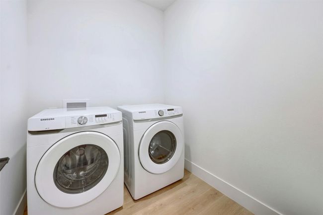 Laundry area featuring washing machine and clothes dryer and light wood-style flooring | Image 20
