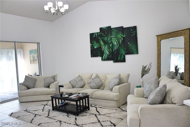 Living area with a notable chandelier, vaulted ceiling, and tile patterned floors | Image 10
