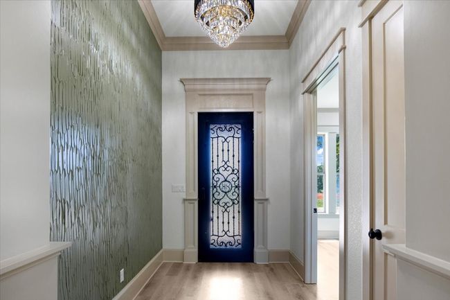 Entrance foyer with light wood-type flooring, crown molding, and a chandelier | Image 7