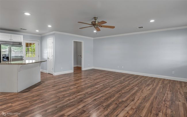 Unfurnished living room featuring visible vents, a ceiling fan, dark wood finished floors, and baseboards | Image 9