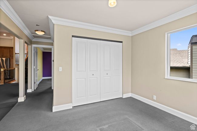 Unfurnished bedroom with crown molding, dark colored carpet, and a closet | Image 14