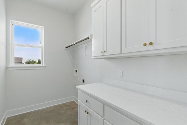 Washroom featuring hookup for a washing machine, hookup for an electric dryer, cabinet space, and baseboards | Image 23