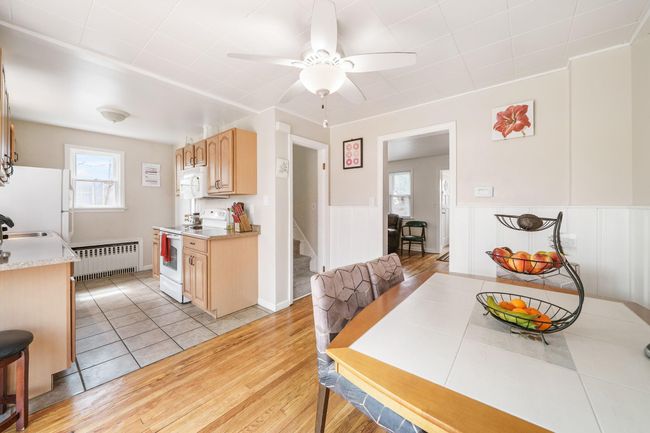 Dining space with stairs, wainscoting, light tile patterned floors, ceiling fan, and radiator | Image 15