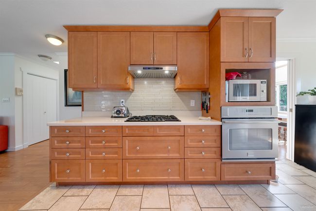 Kitchen with appliances with stainless steel finishes, tasteful backsplash, light countertops, ornamental molding, and under cabinet range hood | Image 21