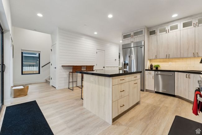Kitchen with stainless steel appliances, light brown cabinetry, light hardwood / wood-style floors, and a center island | Image 16