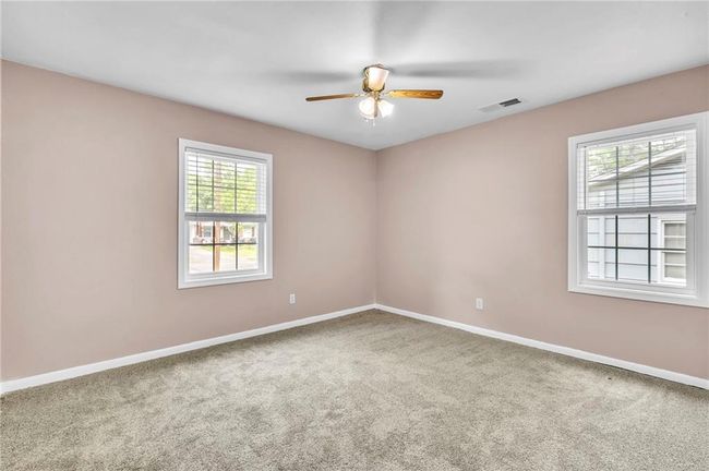 Empty room with carpet floors, a ceiling fan, visible vents, and baseboards | Image 30