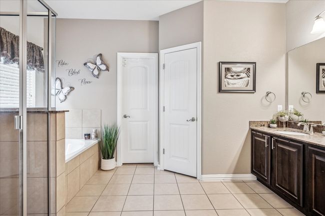 Bathroom with tile patterned flooring, a stall shower, a garden tub, vanity, and baseboards | Image 16