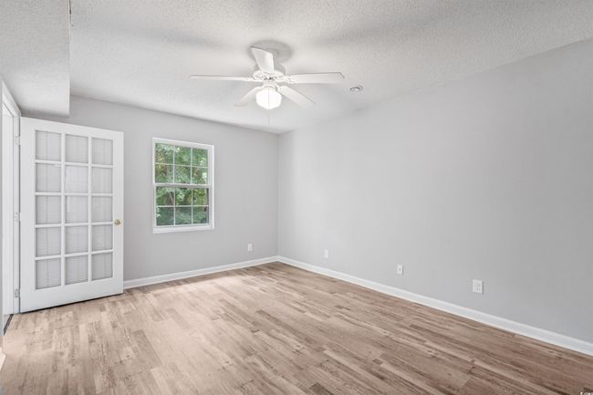 Empty room with wood finished floors, a textured ceiling, and ceiling fan | Image 21