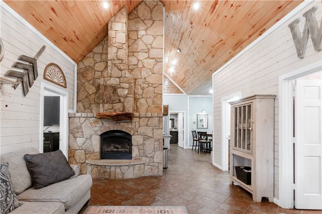 Living room featuring wood walls, a fireplace, high vaulted ceiling, and wood ceiling | Image 4