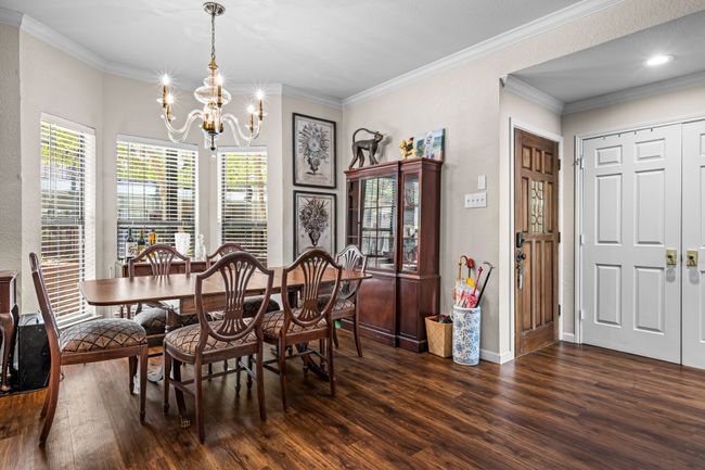 Dining area featuring a chandelier, dark wood-style flooring, and crown molding | Image 11