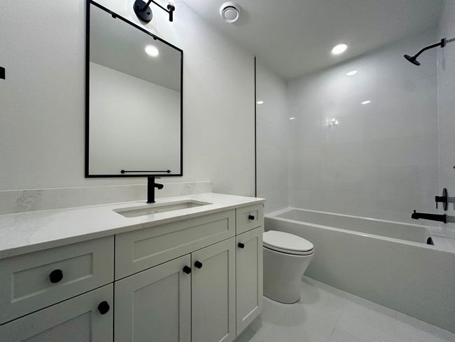 Bathroom with tile patterned floors, vanity, toilet, and tub / shower combination | Image 11