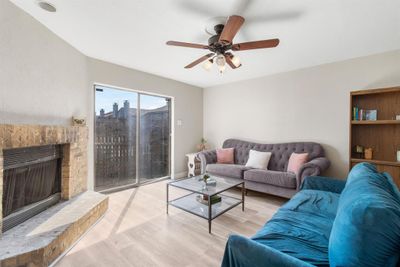 Living room with ceiling fan, light wood-type flooring, and a fireplace | Image 2