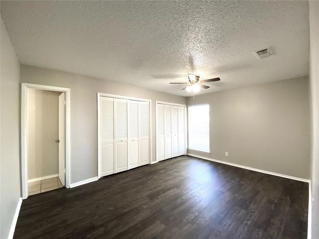 8836 Bedroom featuring ceiling fan, multiple closets, dark wood-style floors, and a textured ceiling | Image 27