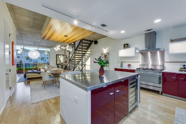 Kitchen featuring wall chimney range hood, rail lighting, stainless steel counters, high end stainless steel range oven, and beverage cooler | Image 19
