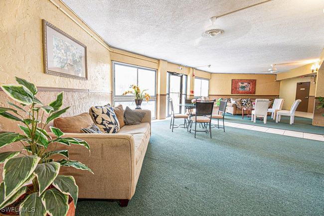 Carpeted living area featuring a textured wall, a ceiling fan, and a textured ceiling | Image 4